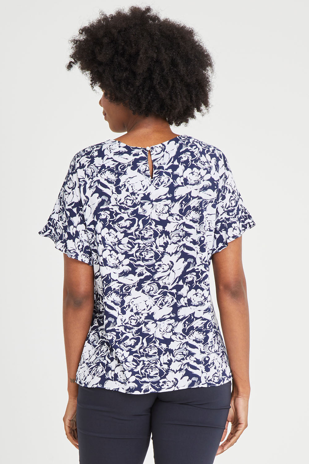 Model Aiyana wearing size 10 of The Frill Sleeve Blouse in colour Navywhite (Blue), from the back