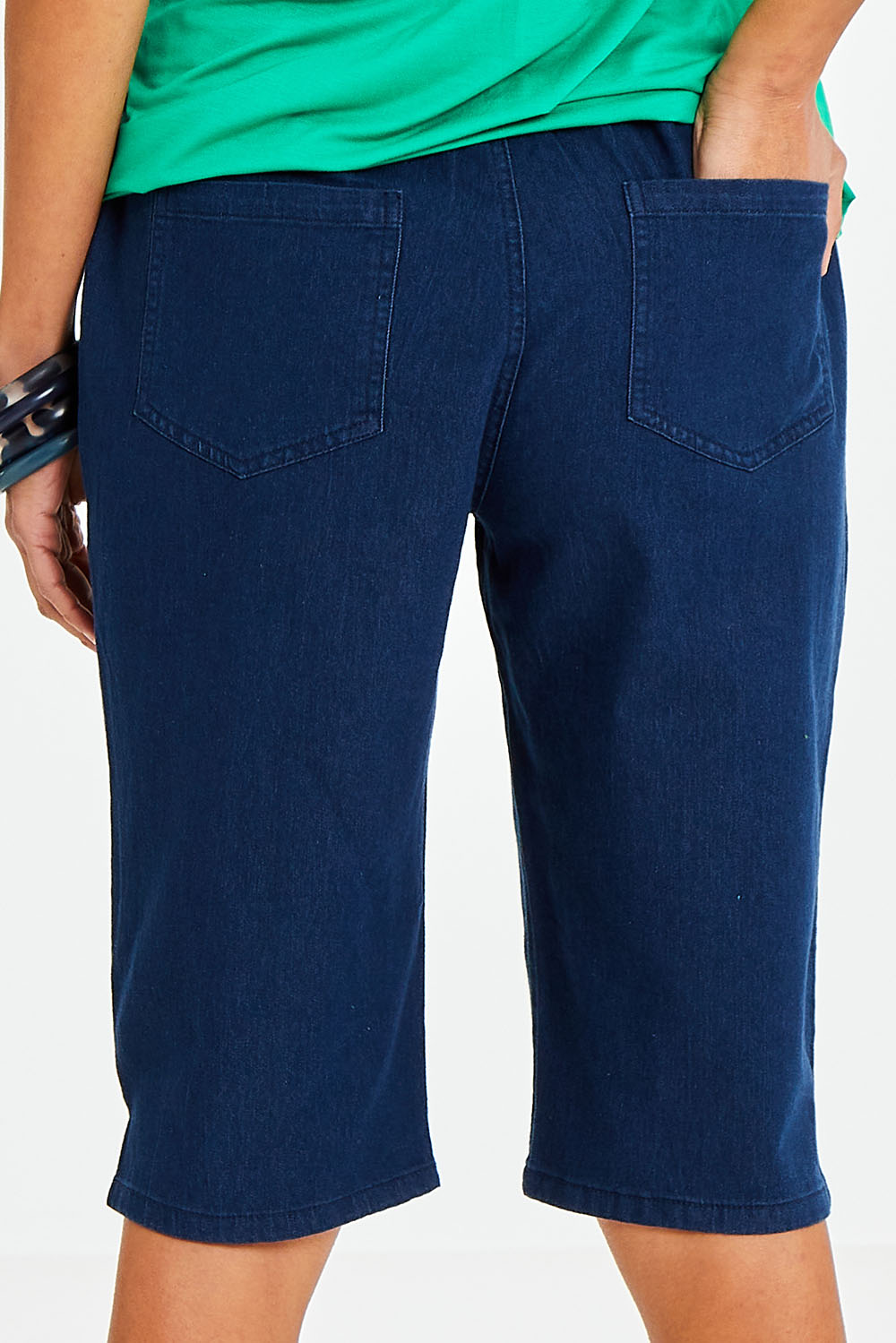 Model Vitoria wearing size 10 of The Bermuda Pull On Short in colour Denim (Blue), from the back