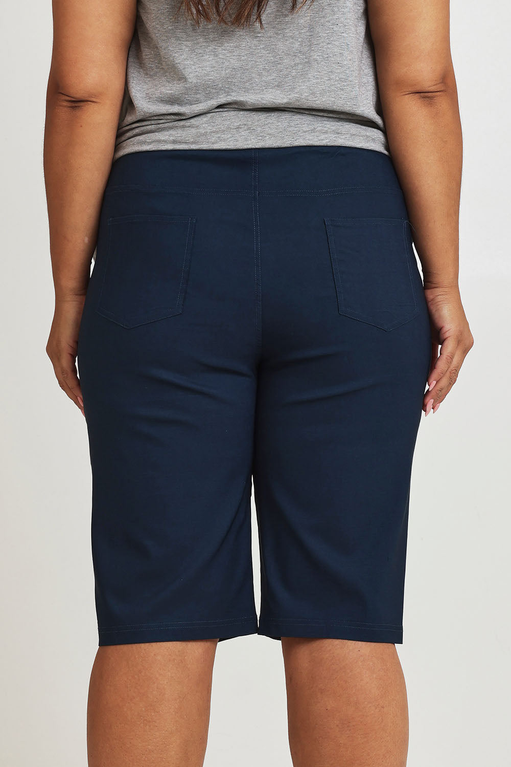 Model Ashleigh wearing size 16 of The Cargo Short in colour Petrol (Blue), from the back