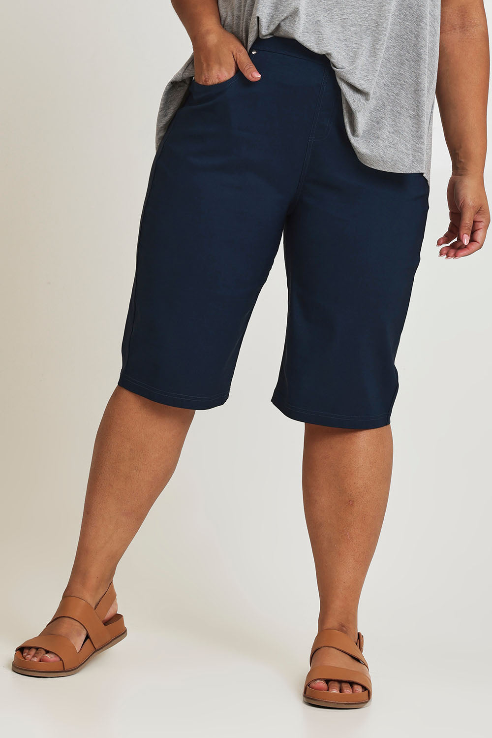 Model Ashleigh wearing size 16 of The Cargo Short in colour Petrol (Blue), from the back