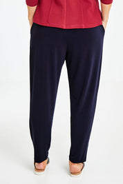Model Laura wearing size 14 of The Pleat Detail Pull On Pant in colour Graphite (Grey), from the back