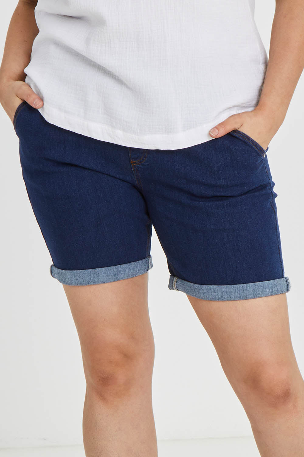 Model Keeara wearing size 16 of The Weekender Shorts in colour Darkdenim (Blue), from the front, cropped image