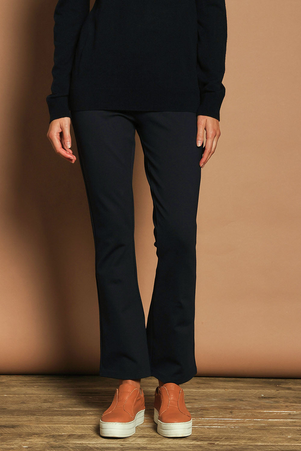 Model Madeline wearing size 10 of The Pull On Ponte Boot Leg Pant in colour Darknavy (Blue), from the front, cropped image