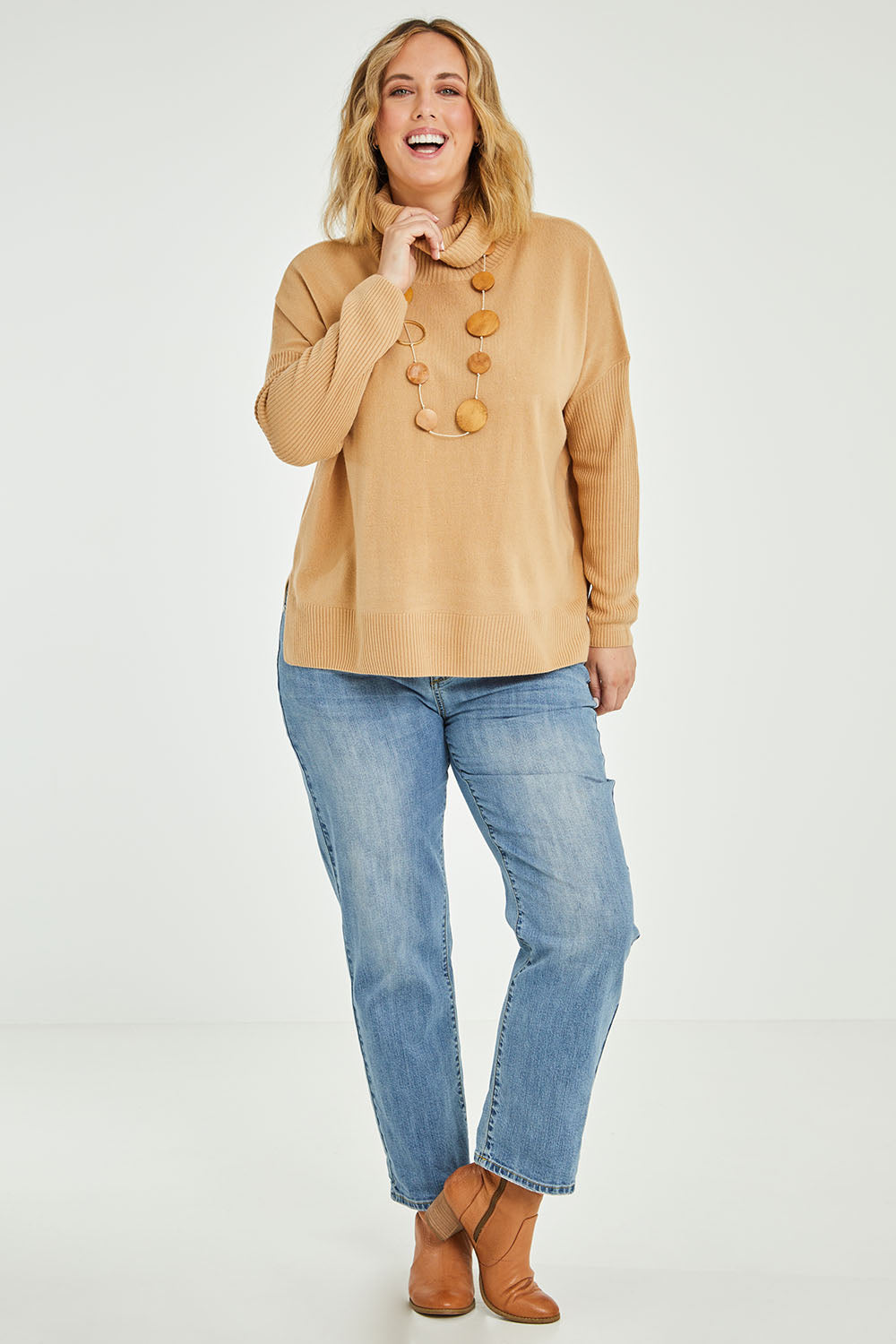 Model Jess wearing size L of The Essential Soft High Low Jumper in colour Camel, from the front, showing the whole outfit