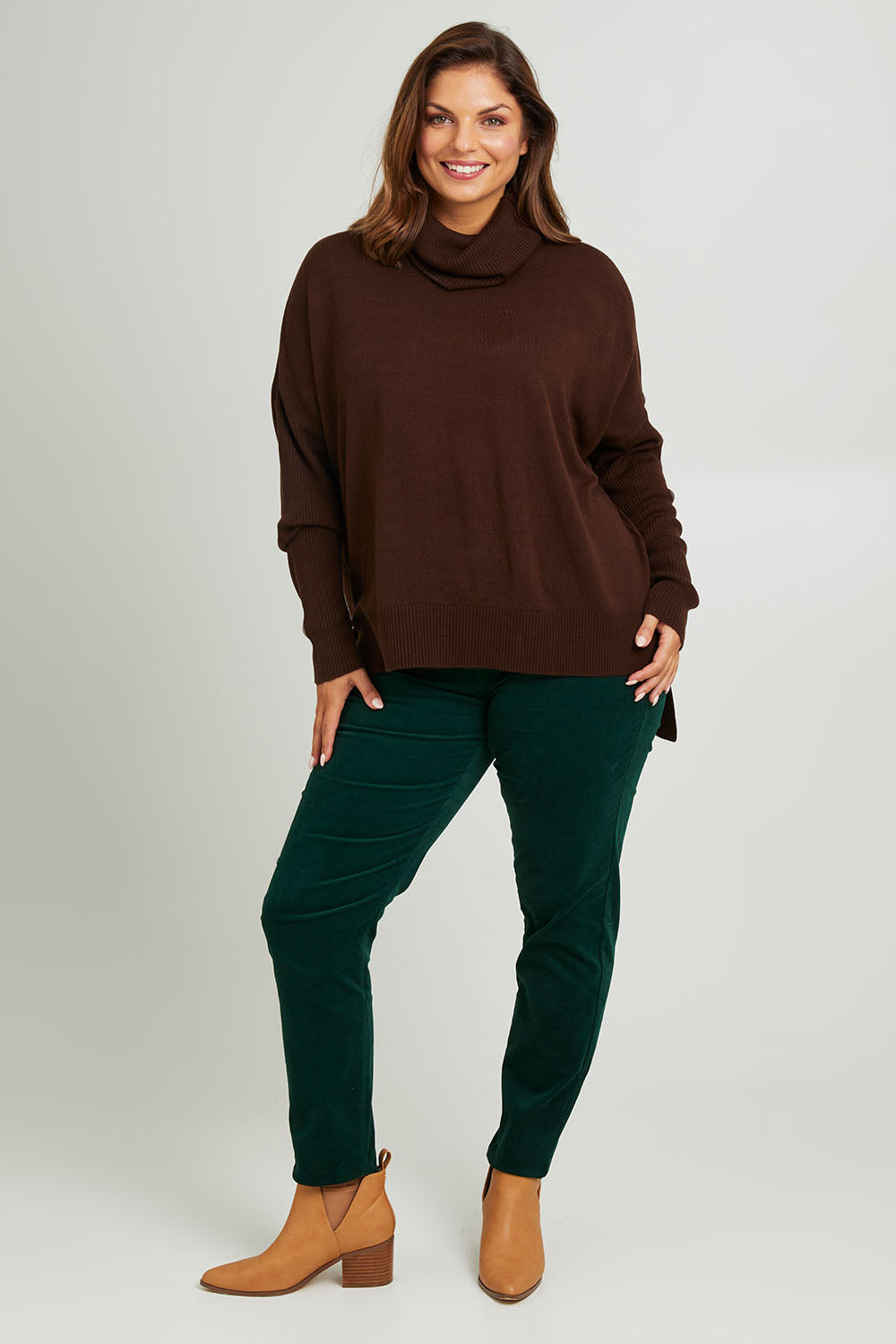 Model Monique wearing size L of The Essential Soft High Low Jumper in colour Chocolate, from the front, showing the whole outfit