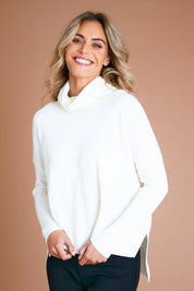 Model Alice wearing size S of The Essential Soft High Low Jumper in colour Snow (White), from the front, showing the whole outfit