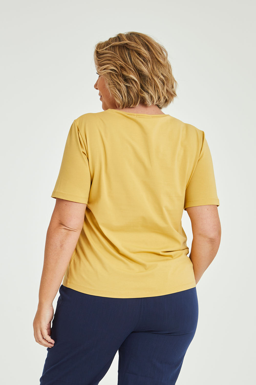Model Fiona wearing size 16 of The Keepers Tee in colour Camel, from the back