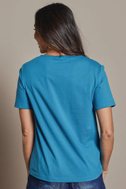Model Amanda wearing size 10 of The Keepers Tee in colour Turquoise (Blue), from the back