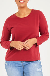 Model Noli wearing size 14 of The Keepers Long Sleeve Tee in colour Shiraz (Red), from the front, cropped image