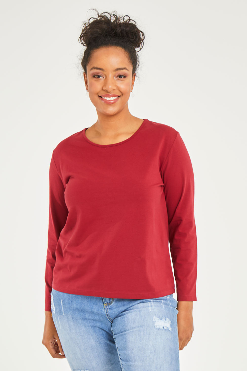 Model Noli wearing size 14 of The Keepers Long Sleeve Tee in colour Shiraz (Red), from the front, cropped image