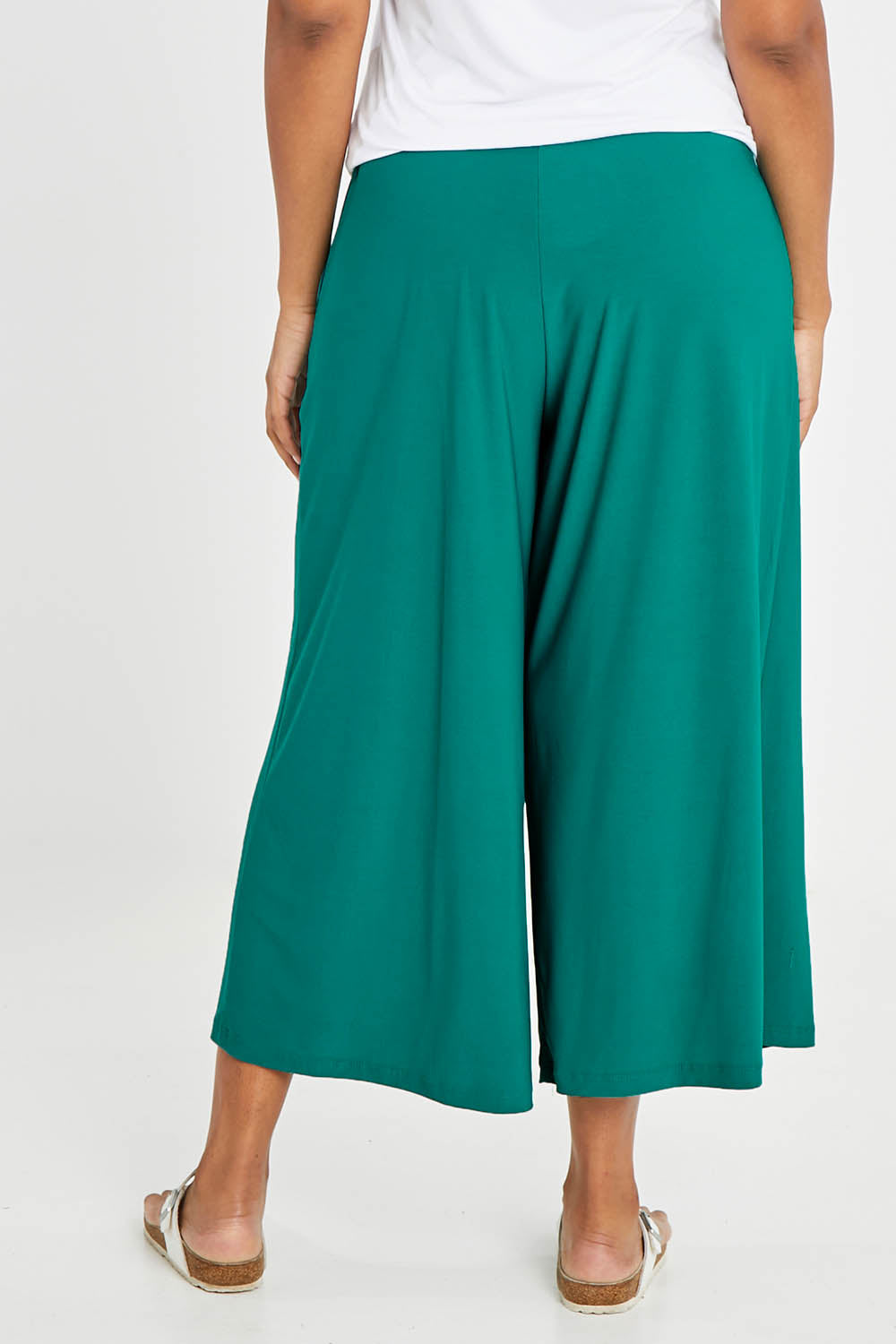 Model Noli wearing size 14 of The Recycled Pleated Culottes in colour Emerald (Green), from the back