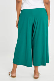 Model Noli wearing size 14 of The Recycled Pleated Culottes in colour Emerald (Green), from the back
