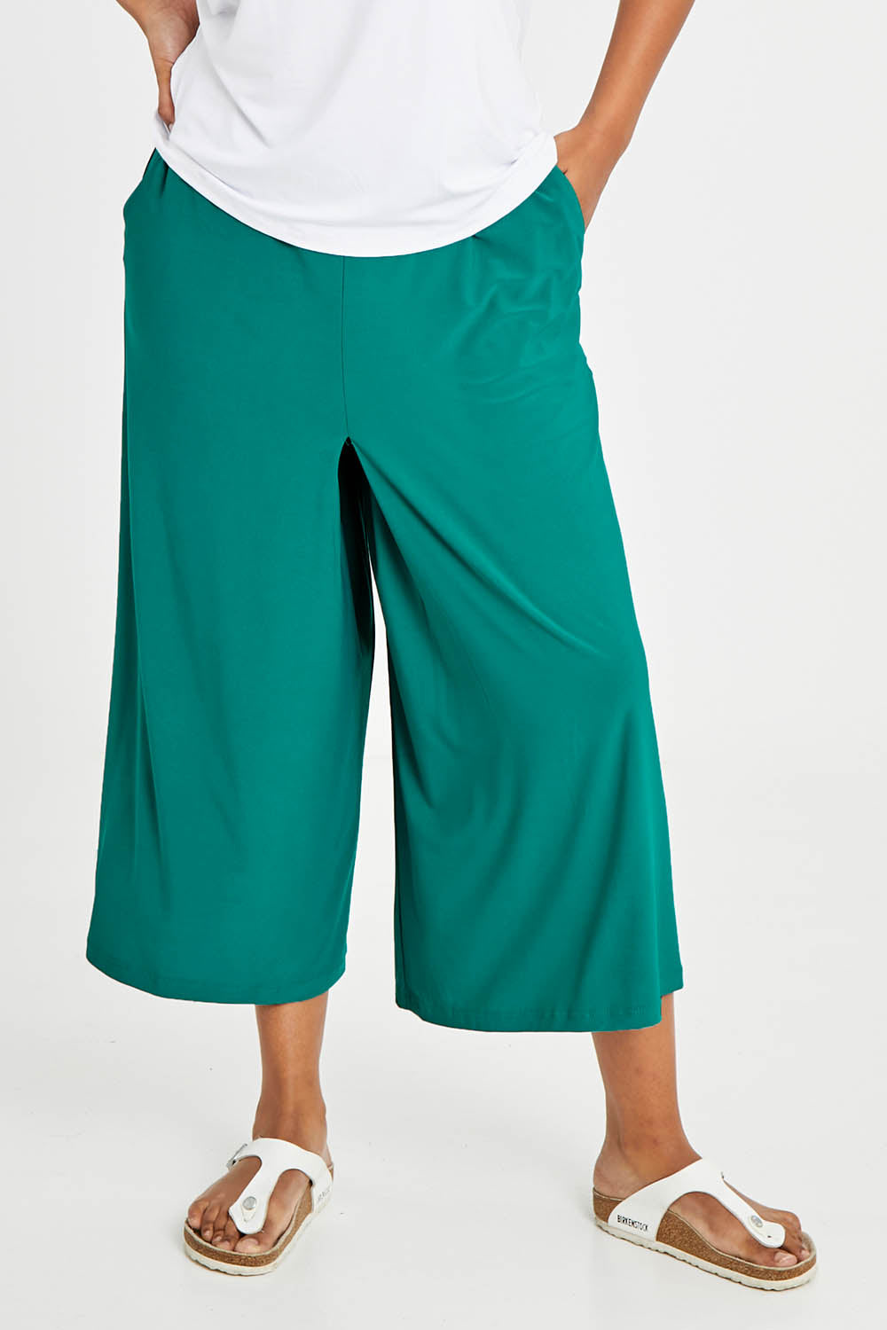 Model Noli wearing size 14 of The Recycled Pleated Culottes in colour Emerald (Green), from the front, cropped image