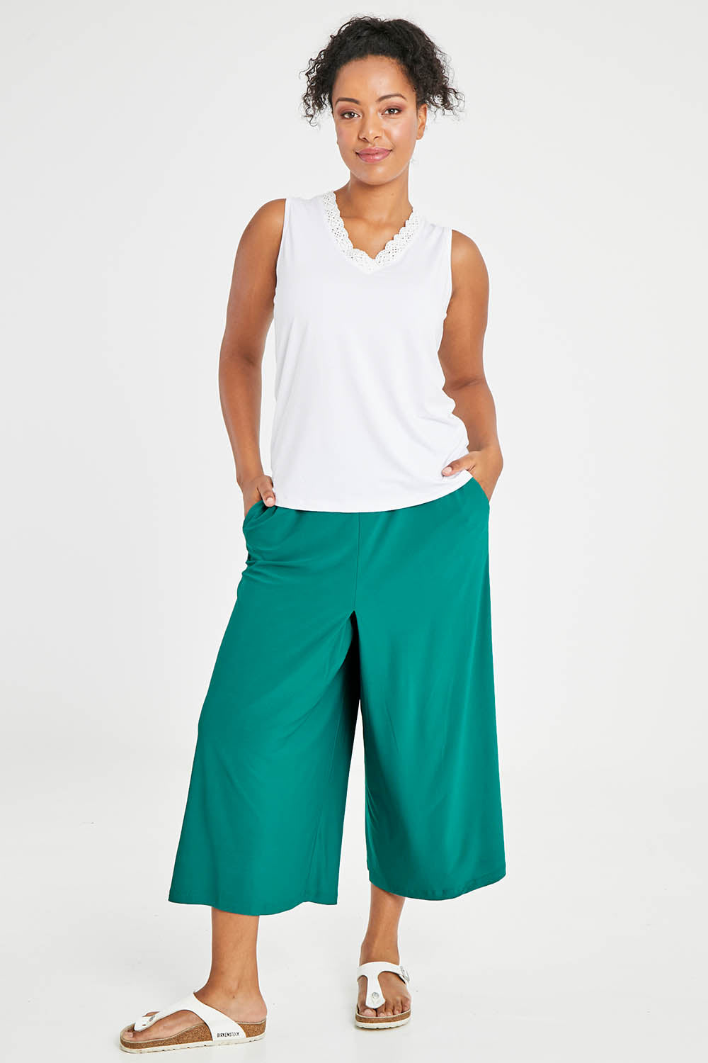Model Noli wearing size 14 of The Recycled Pleated Culottes in colour Emerald (Green), from the front, showing the whole outfit