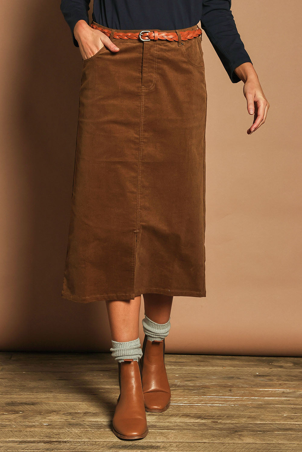 Model Madeline wearing size 10 of The 5 Pocket Cord Midi Skirt in colour Malt, from the front, cropped image