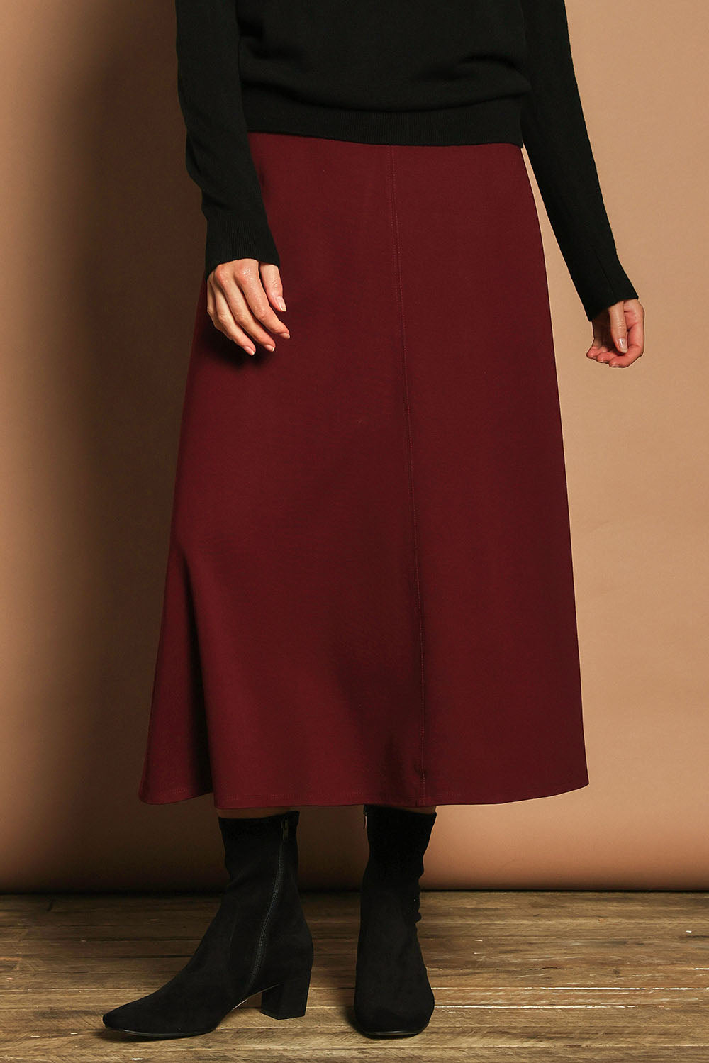 Model Madeline wearing size 10 of The Fit And Flare Ponte Skirt in colour Cognac (Red), from the front, cropped image