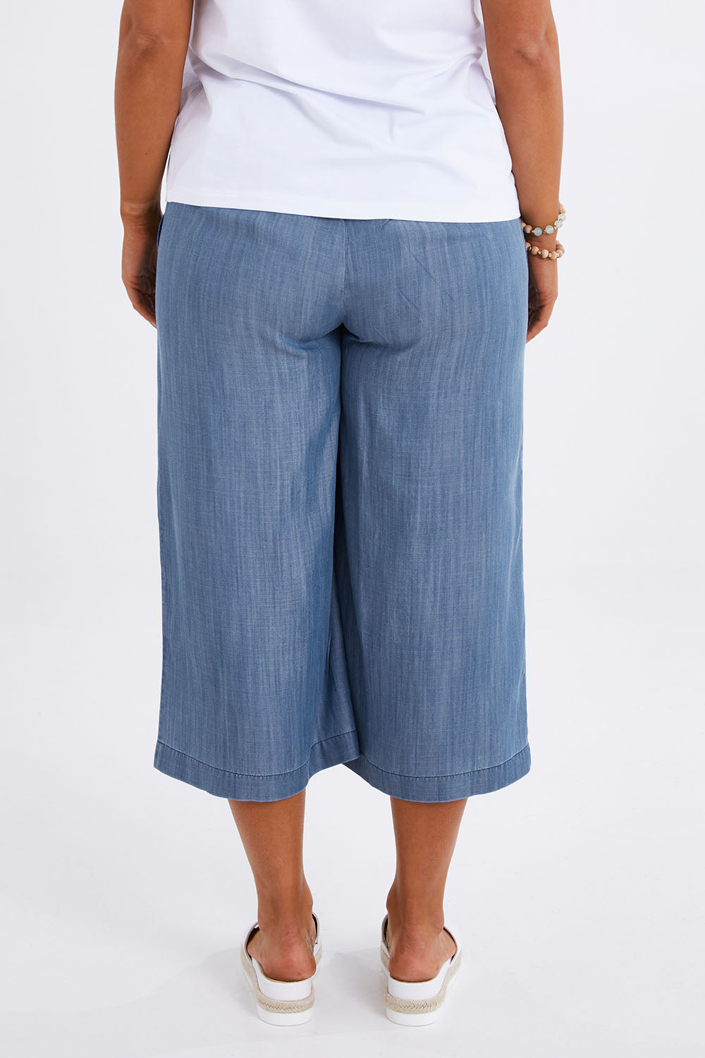 Model Monique wearing size 14 of The Chambray Pull On Cullotes in colour Bluedenim (Blue), from the back