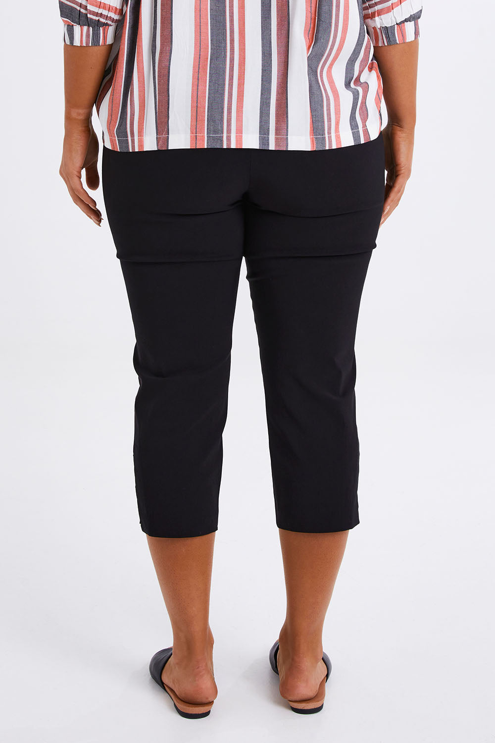 Model Monique wearing size 14 of The X Detail Capri Pant in colour Black (Black), from the back