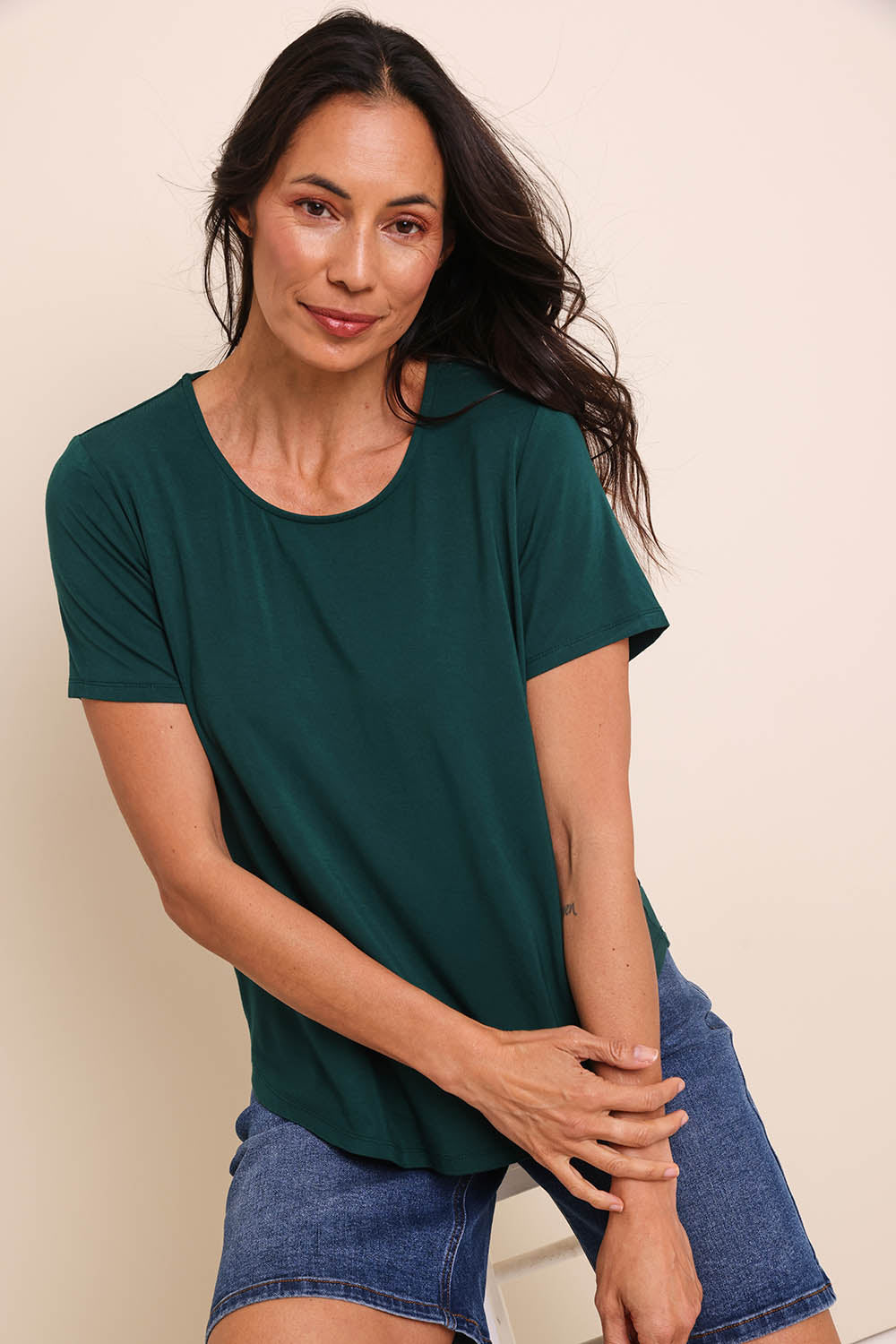 Model Amandam wearing size 10 of the The Bamboo Curved Hem Tee – Forest in colour Forest, in a cropped view
