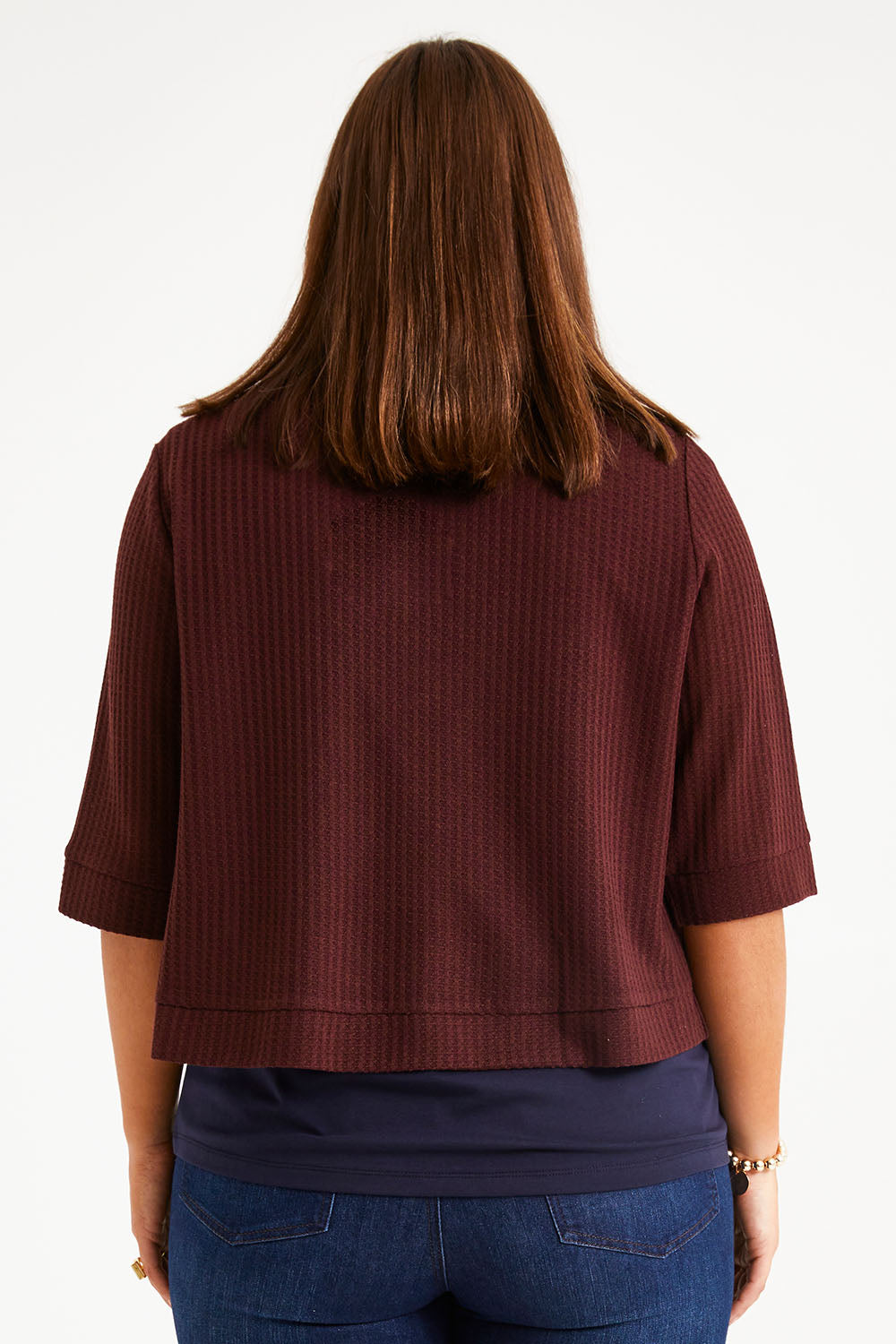Model Monique wearing size 14 of The Textured Shrug in colour Mulberry (Purple), from the back