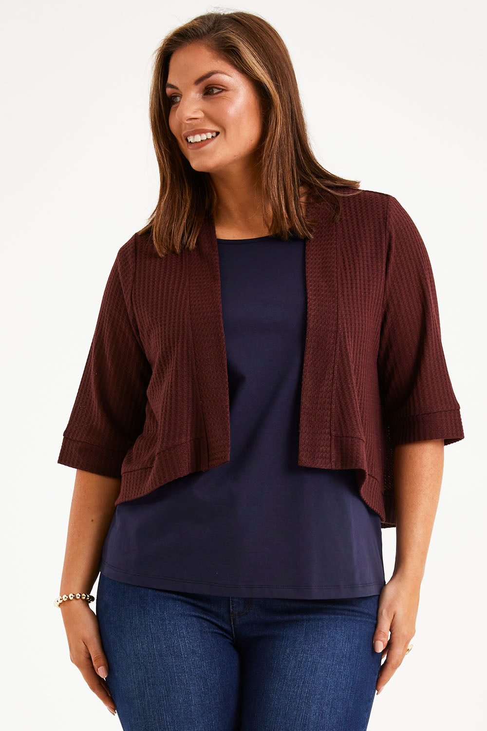 Model Monique wearing size 14 of The Textured Shrug in colour Mulberry (Purple), from the front, cropped image