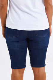 Model Monique wearing size 14 of The Pull On Denim Short in colour Darkdenim (Blue), from the back