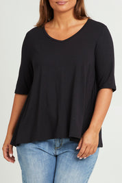 Model Monique wearing size 14 of The Luxe A Line Tee in colour Black (Black), from the front, cropped image