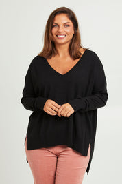 Model Monique wearing size L of The High Low V Neck Jumper in colour Black (Black), from the front, cropped image