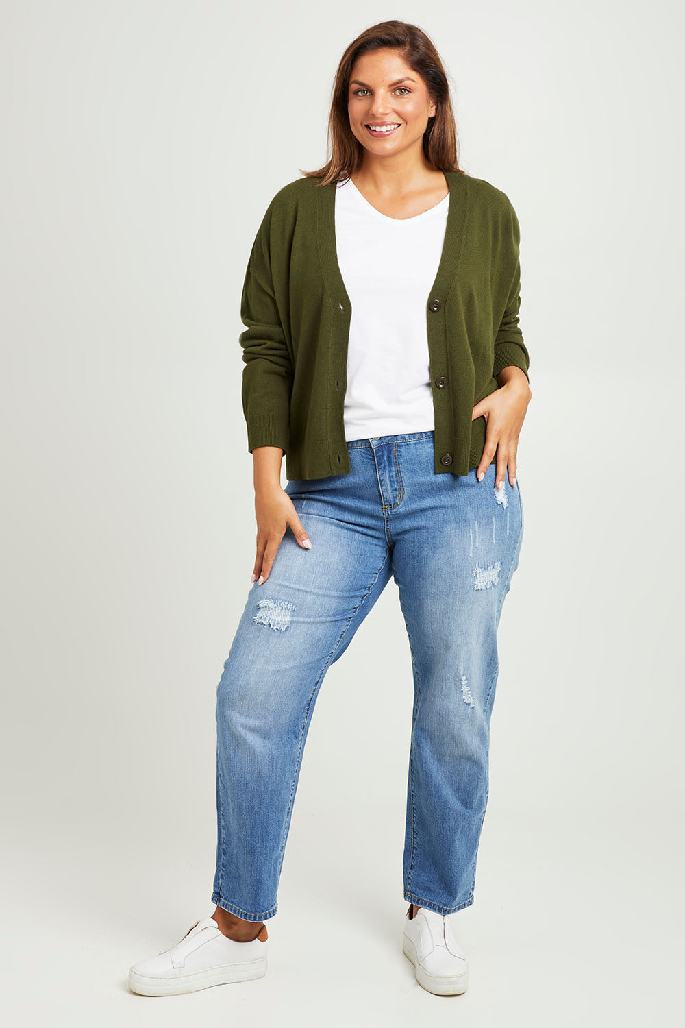 Model Monique wearing size L of The Soft Cropped Cardigan in colour Darkolive (Green), from the front, showing the whole outfit