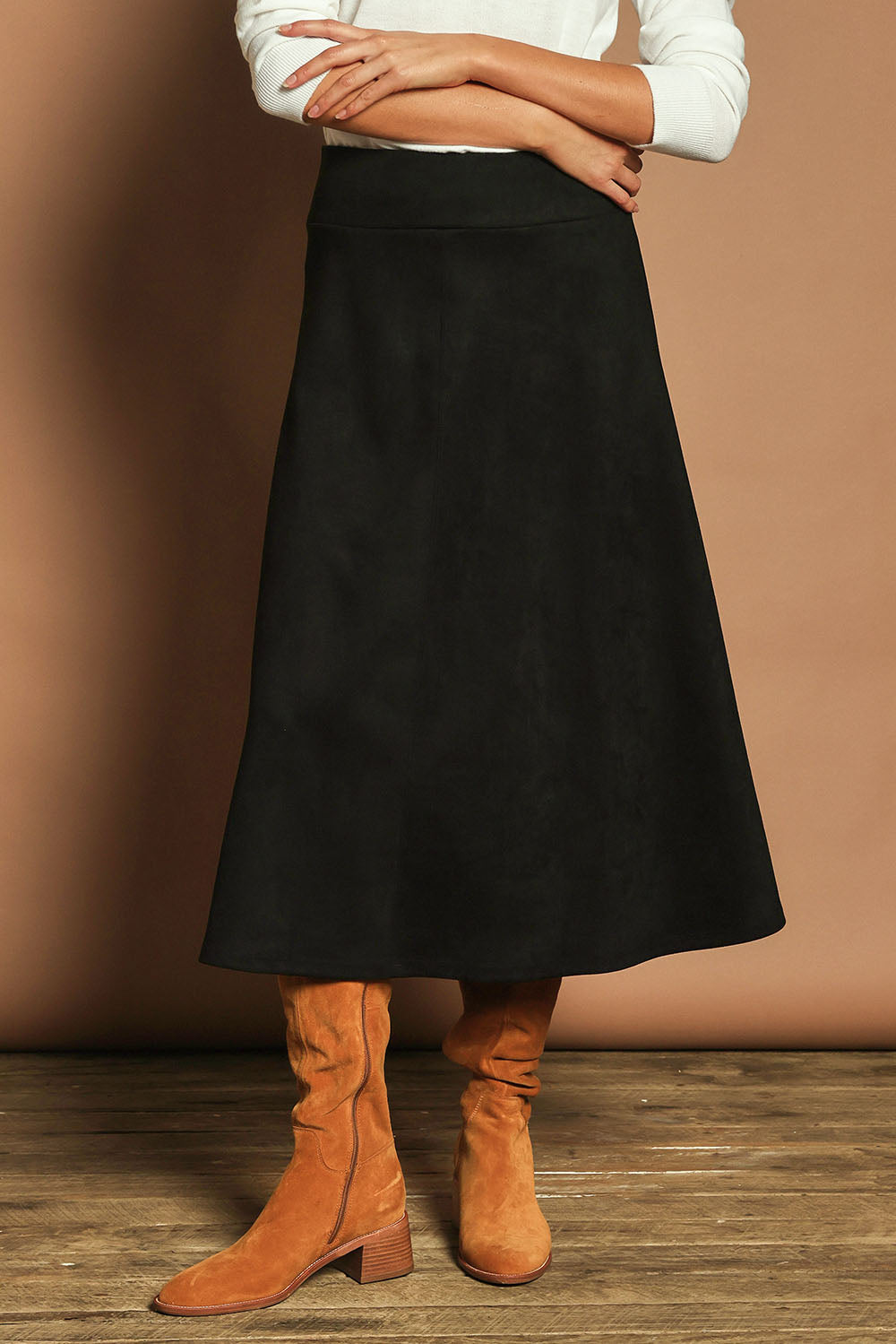 Model Madeline wearing size 10 of The Luxe Faux Suede Skirt in colour Black (Black), from the front, cropped image