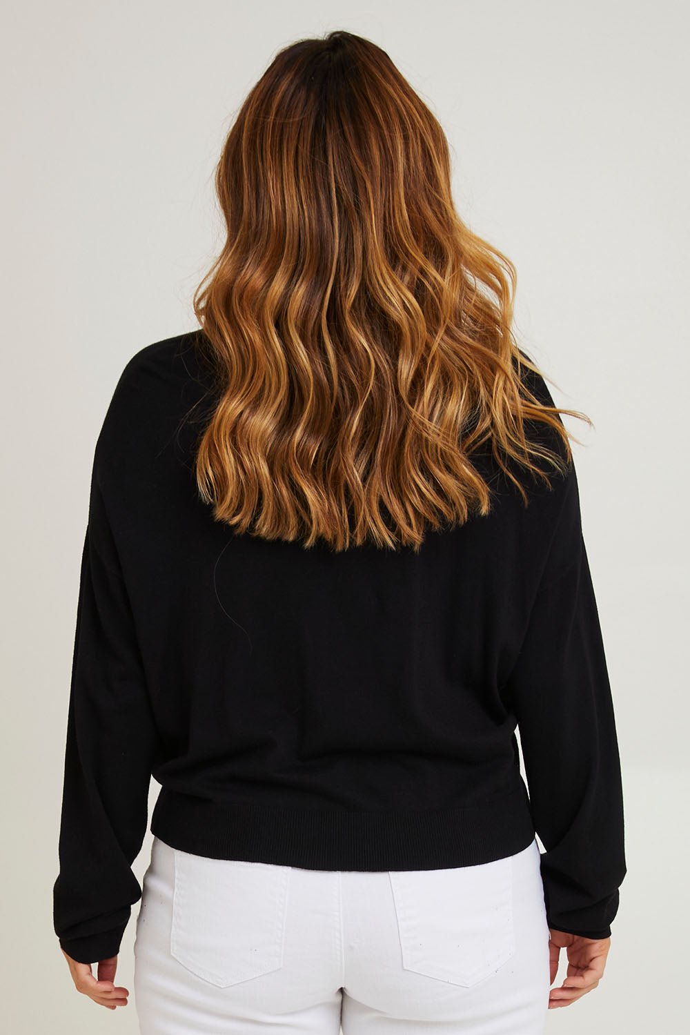Model Laura wearing size L of The All Season Cropped Cardigan in colour Black (Black), from the back