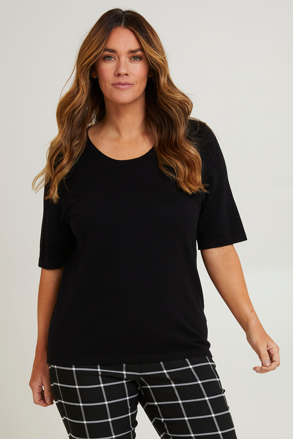 Model Laura wearing size L of The All Season Crew Neck Knit Tee in colour Black (Black), from the front, cropped image