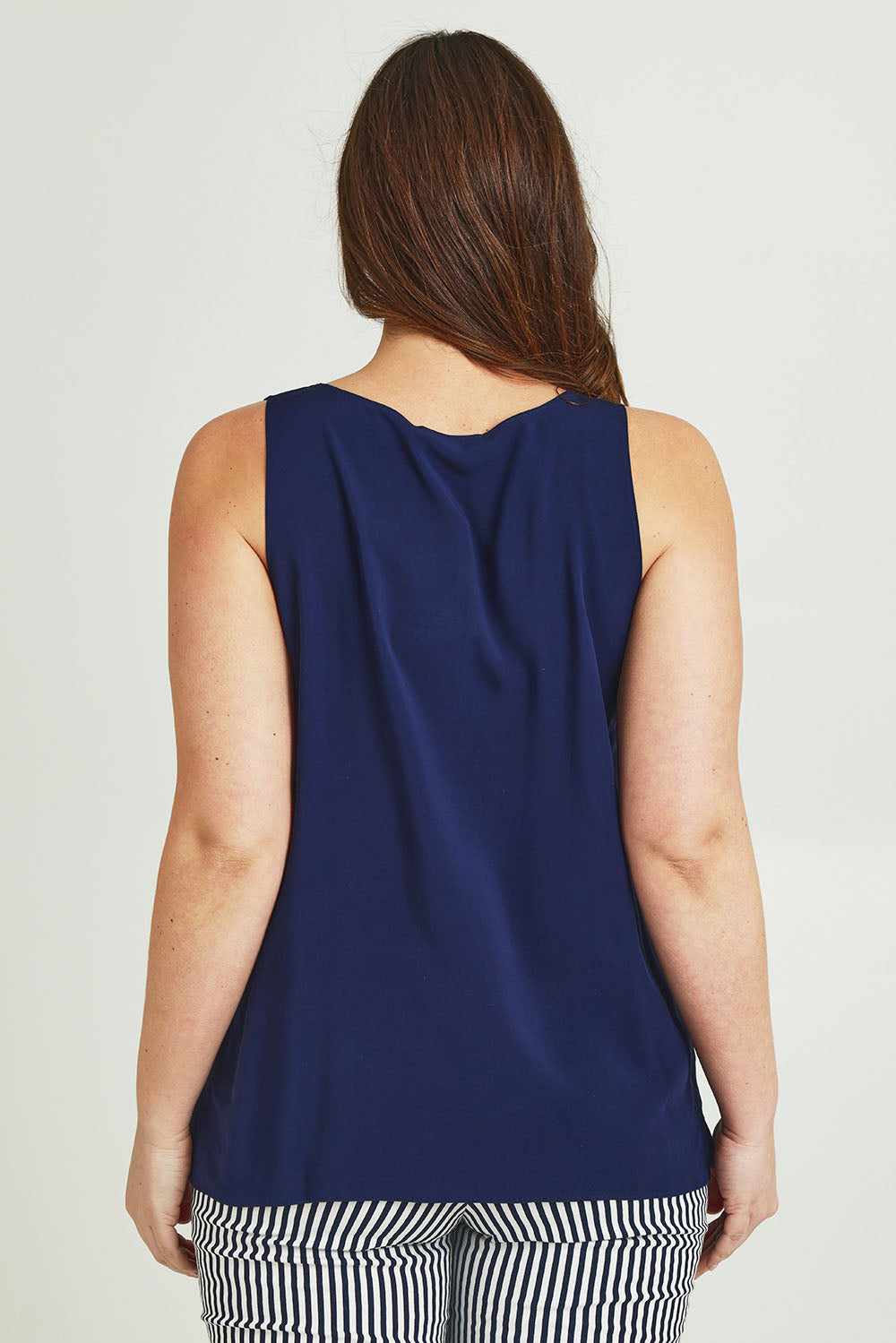 Model Jane wearing size 14 of The Keepers Essential Woven Tank in colour Navy (Blue), from the back
