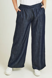 Model Jane wearing size 14 of The Luxe Chambray Pull On Pant in colour Darkdenim (Blue), from the front, cropped image