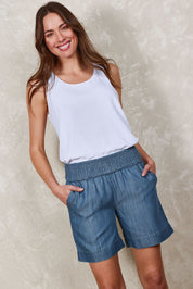 Model Madeline wearing size 10 of The Shirred Waist Pull On Shorts in colour Denimblue (Blue), from the front, showing the whole outfit