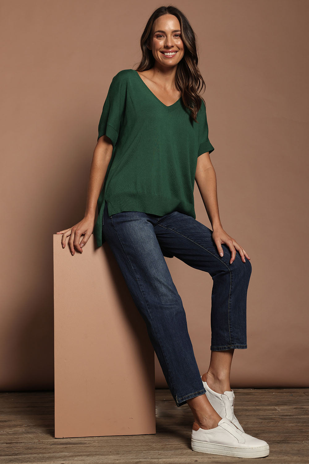 Model Madeline wearing size S of The All Season V Neck High Low Tee in colour Cactus (Green), from the front, showing the whole outfit