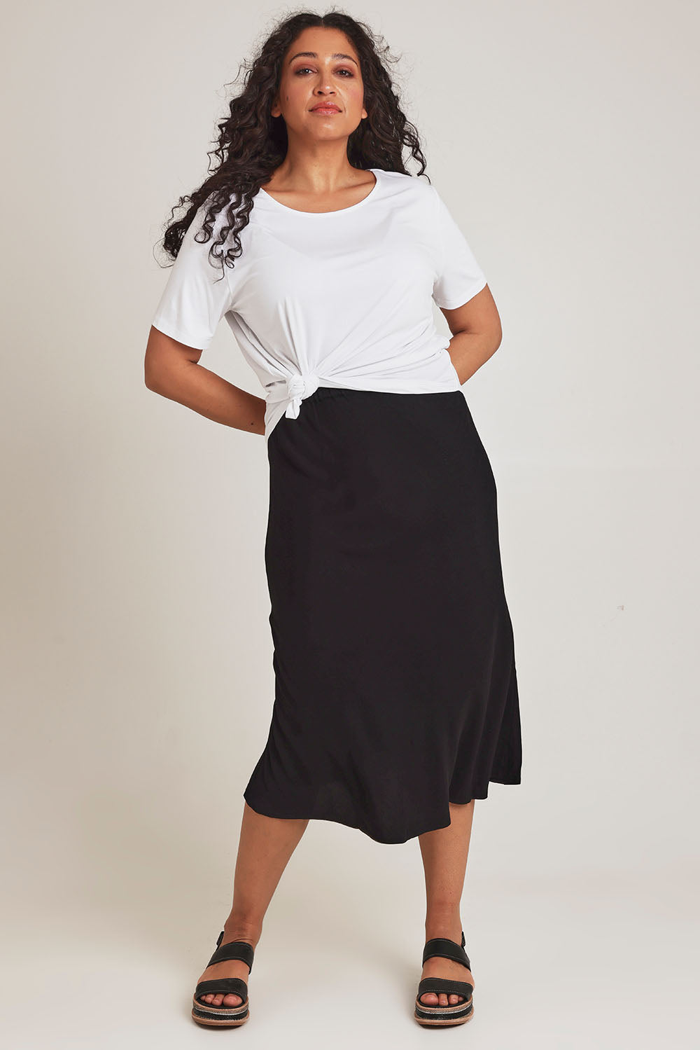 Model Terri-Leigh wearing size 14 of The Pull On Bias Skirt in colour Black (Black), from the front, showing the whole outfit