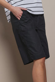 Model Madeline wearing size 10 of The Rib Waistband Short in colour Black (Black), from the front, cropped image