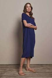 Model Madeline wearing size 10 of The Pack & Go Luxe Bamboo Pull On Dress with Pockets in colour Frenchnavy (Blue), from the front, showing the whole outfit