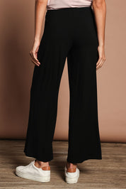 Model Madeline wearing size 10 of The Pack & Go Luxe Bamboo Wide Leg Pant in colour Black (Black), from the back