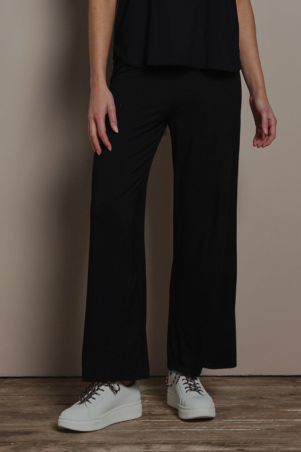 Model Madeline wearing size 10 of The Pack & Go Luxe Bamboo Wide Leg Pant in colour Black (Black), from the front, cropped image