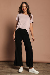 Model Madeline wearing size 10 of The Pack & Go Luxe Bamboo Wide Leg Pant in colour Black (Black), from the front, showing the whole outfit