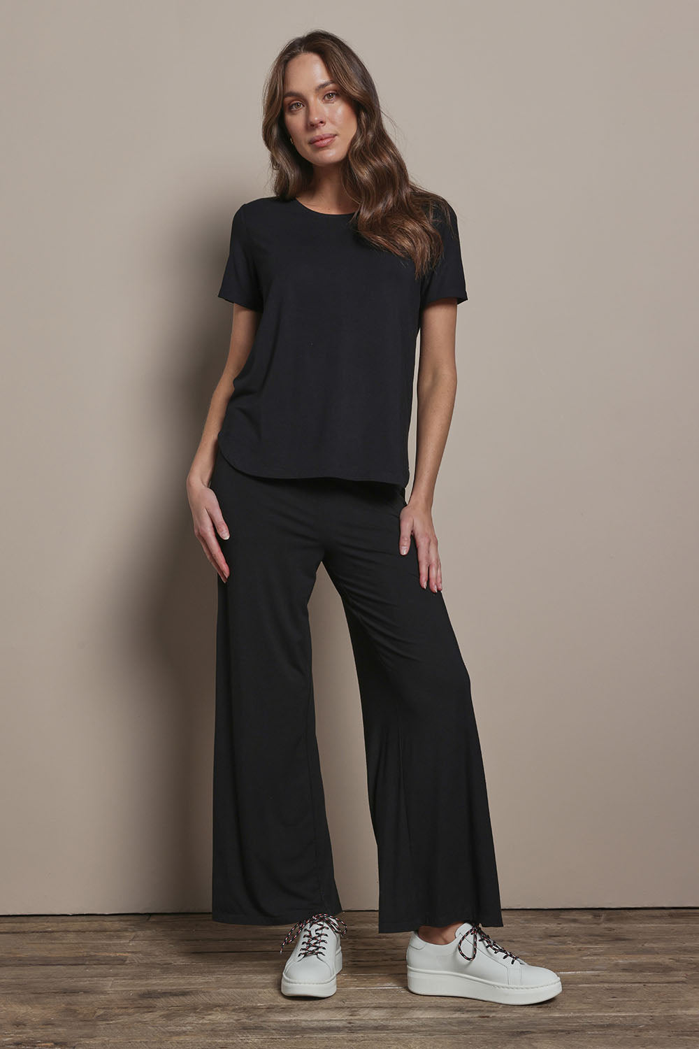 Model Madeline wearing size 10 of The Pack & Go Luxe Bamboo Wide Leg Pant in colour Black (Black), from the front, showing the whole outfit