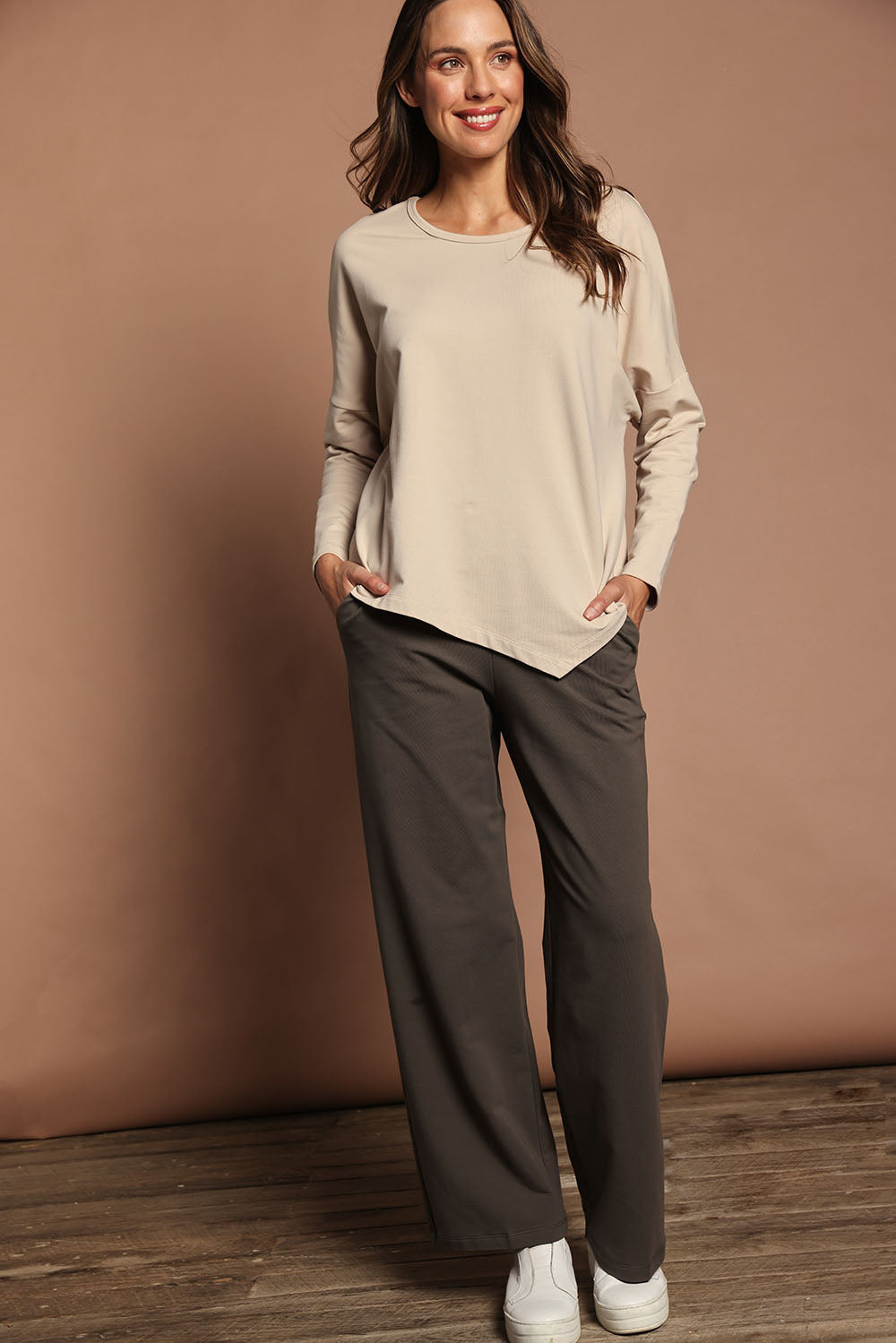 Model Madeline wearing size 10 of The Cotton Comfort Asymmetric Tee in colour Almond, from the front, showing the whole outfit