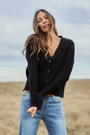 Model Amanda wearing size S of The Cable Knit Button Up Cardigan in colour Black (Black), from the front, showing the whole outfit