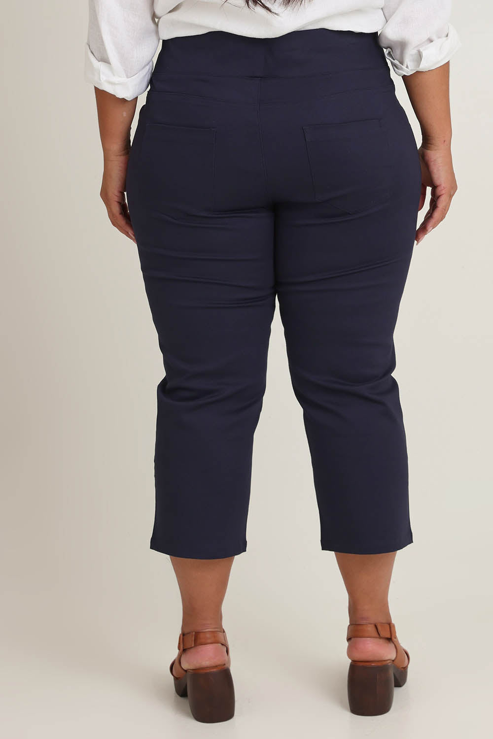 Model Ashleigh wearing size 16 of The Pull On Cotton Cropped Pant With Pockets in colour Navy (Blue), from the back