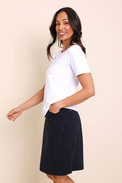 Model Amandam wearing size 10 of the The Lightweight Cotton Blend Stretch Skirt – Navy in colour Navy, from an angle