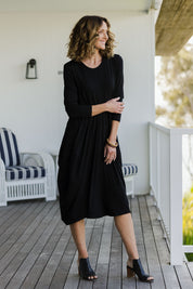 Model Emma wearing size 10 of The Bounce Dress in colour Black (Black), from the front, showing the whole outfit