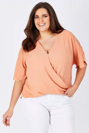 Model Mae wearing size 16 of The Cut Out Shoulder Blouse in colour Clay, from the front, cropped image