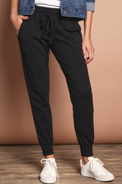Model Madeline wearing size 10 of The Basic Keeper Pant in colour Black (Black), from the front, cropped image